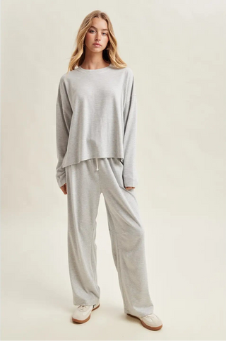 Woman wearing a light gray loungewear set on a plain background