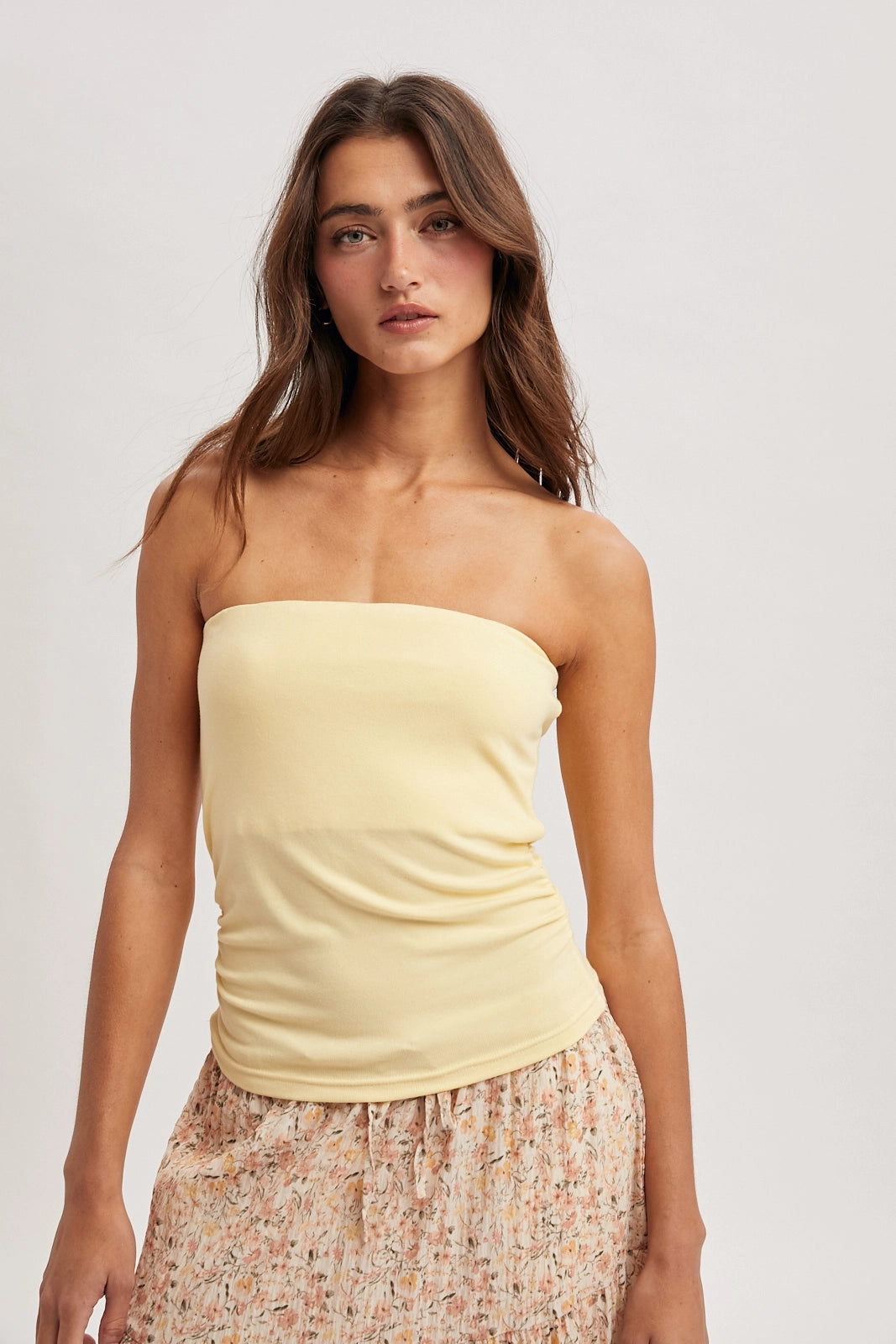 Women wearing a yellow tube top on a plain background.