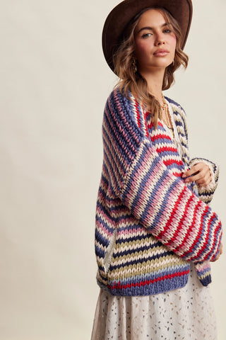 Woman wearing a colorful striped sweater and brown hat against a plain background
