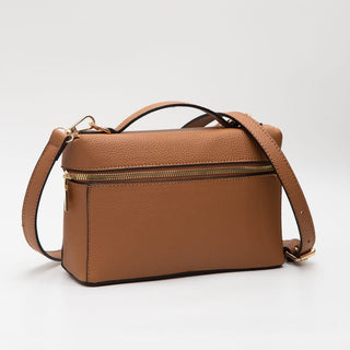 A brown pebbled leather rectangular handbag with a top handle, a zippered top, and an adjustable shoulder strap, photographed on a light gray studio background.