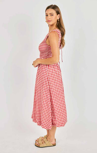 Woman wearing a red and white checkered dress on a plain background