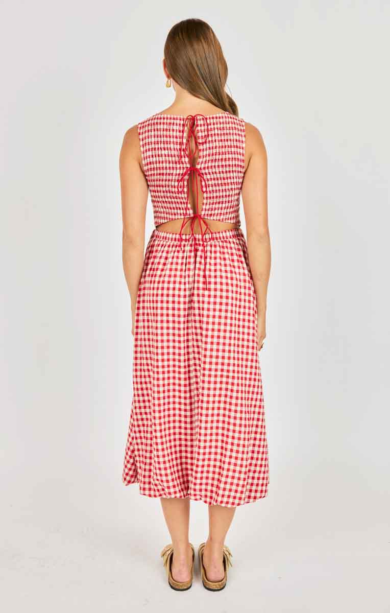 Woman wearing a red and white checkered dress with a tie back detail on a plain background