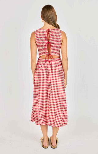 Woman wearing a red and white checkered dress with a tie back detail on a plain background