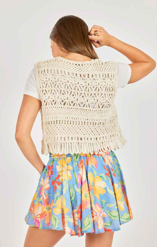 Woman wearing a white crochet top and colorful floral skirt on a white background