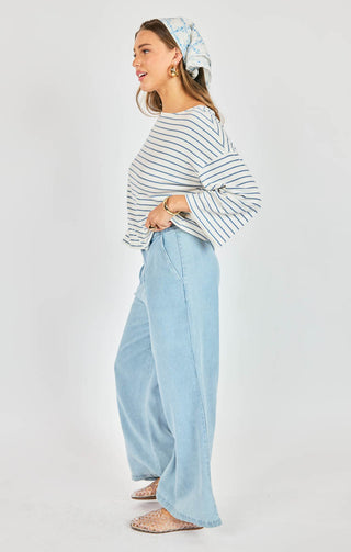 Woman wearing a striped sweater and light blue pants on a white background
