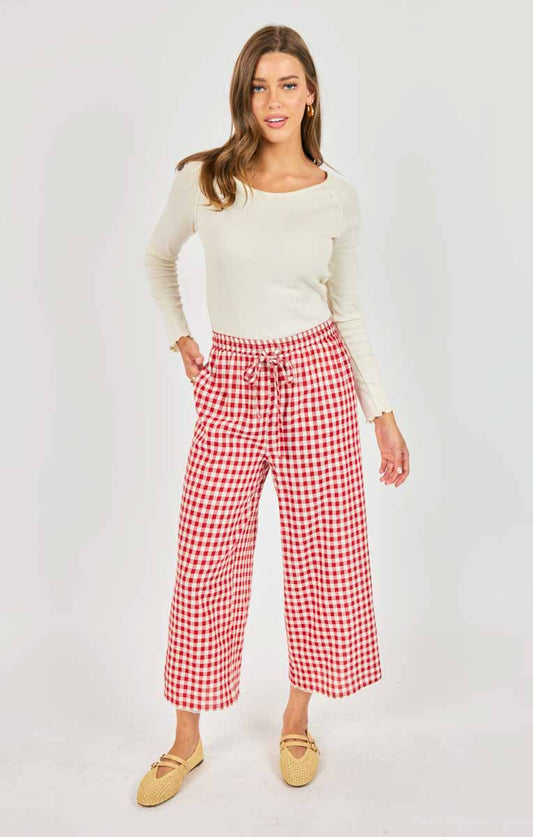 Woman wearing a white top and red checkered pants on a white background