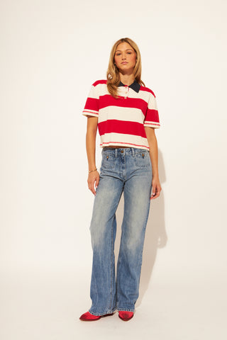 Woman wearing a red and white striped shirt and blue jeans on a white background