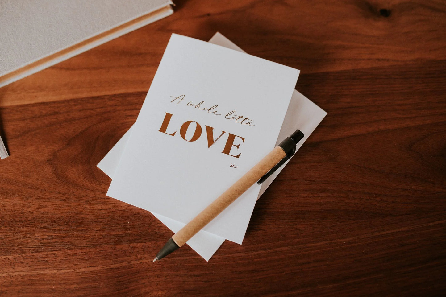 Stack of cards with 'A whole lotta love' text on a wooden surface with a pen.