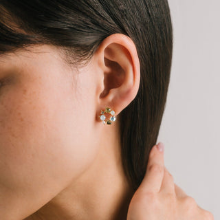 Close-up of an ear wearing a floral earring with a neutral background