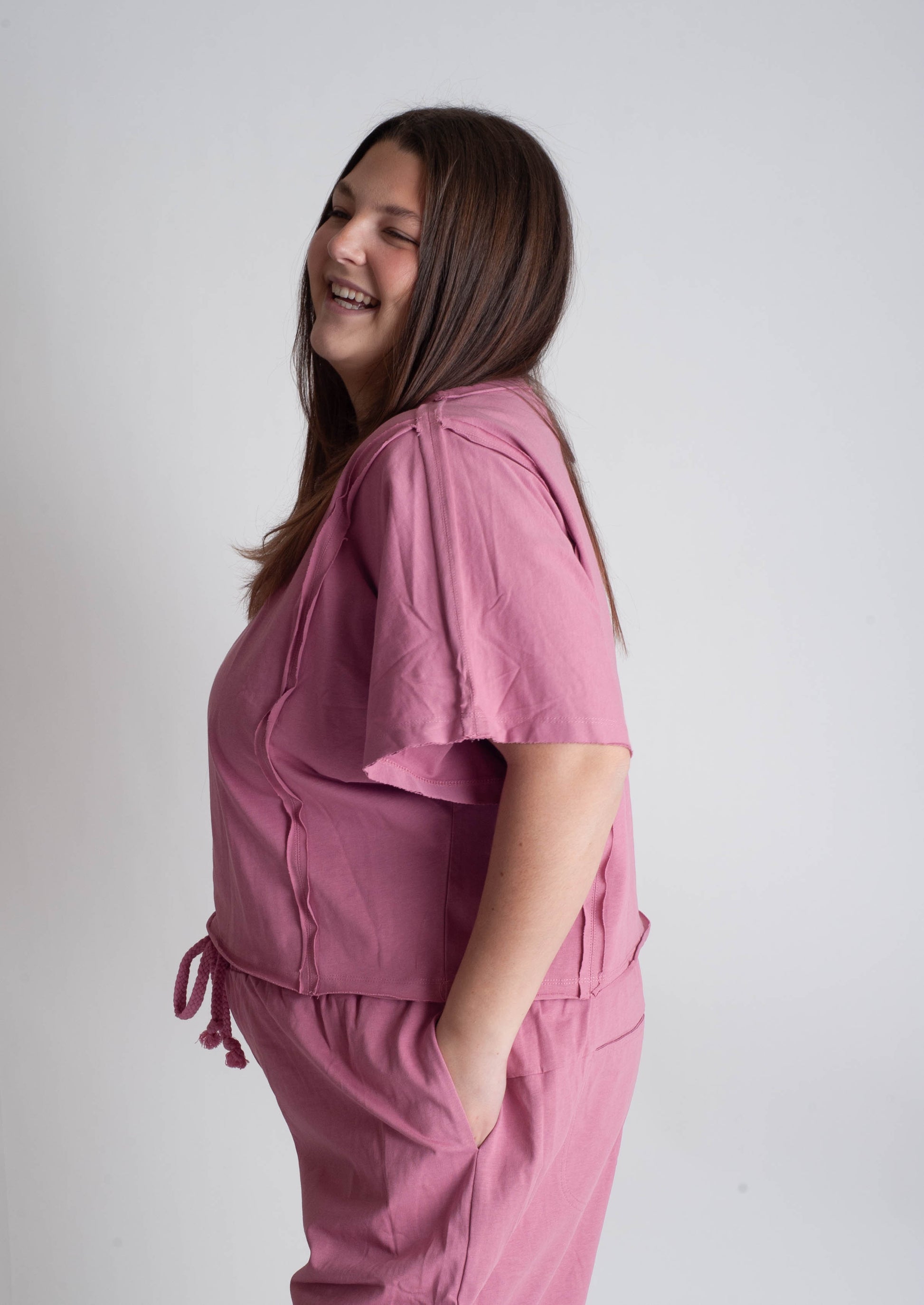 Woman wearing a pink scrub set against a plain background