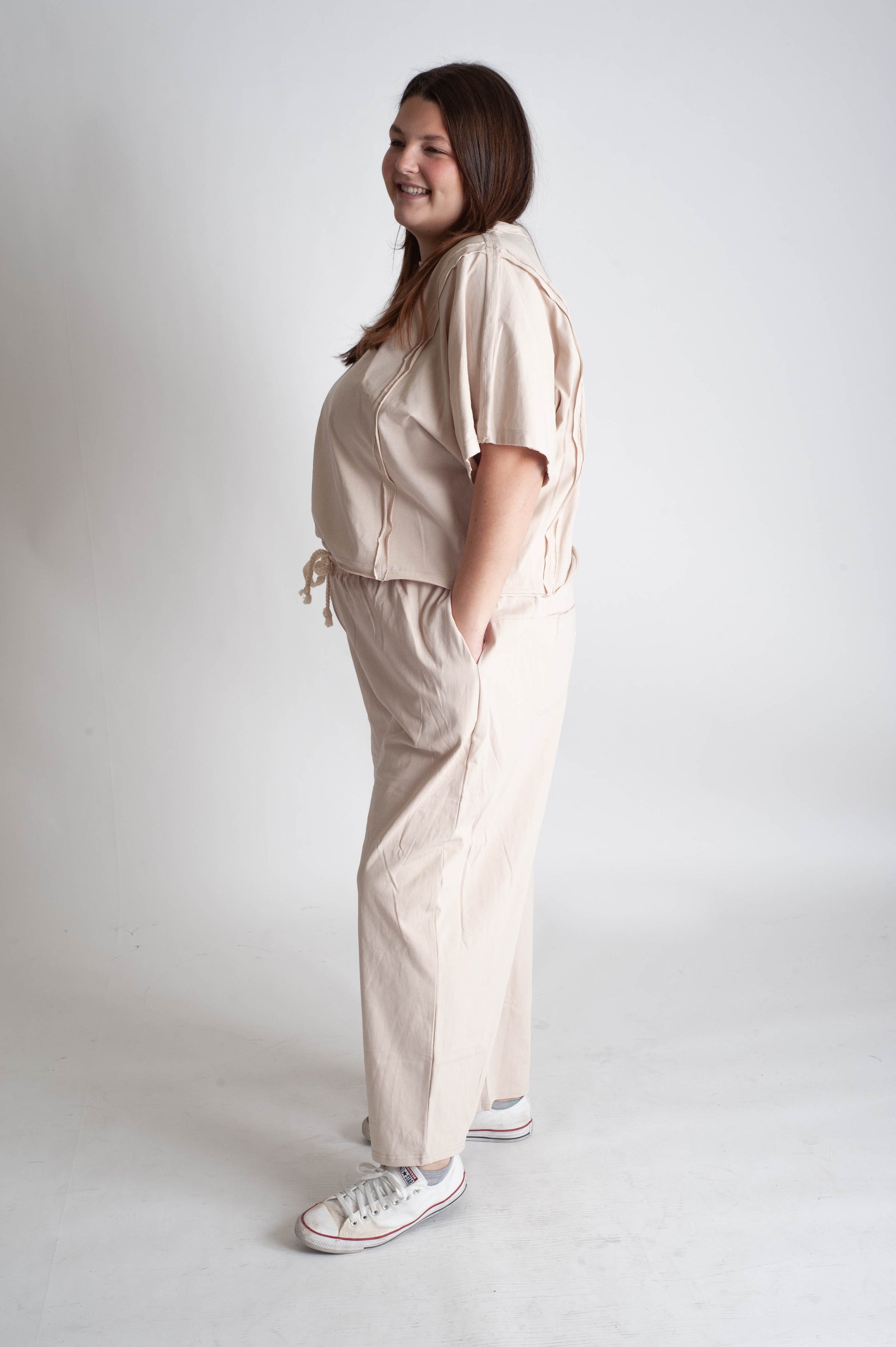 Woman wearing a beige outfit with a matching top and pants on a white background