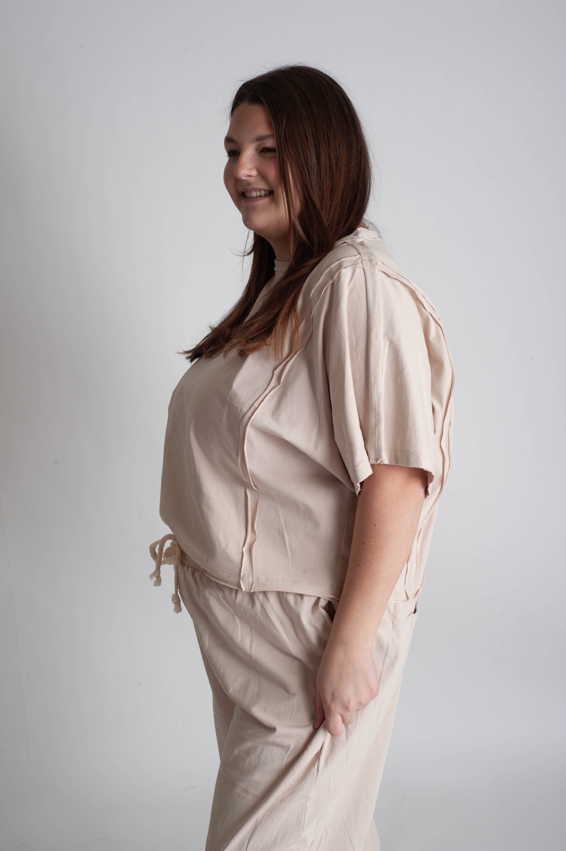 Woman wearing a beige outfit against a plain background
