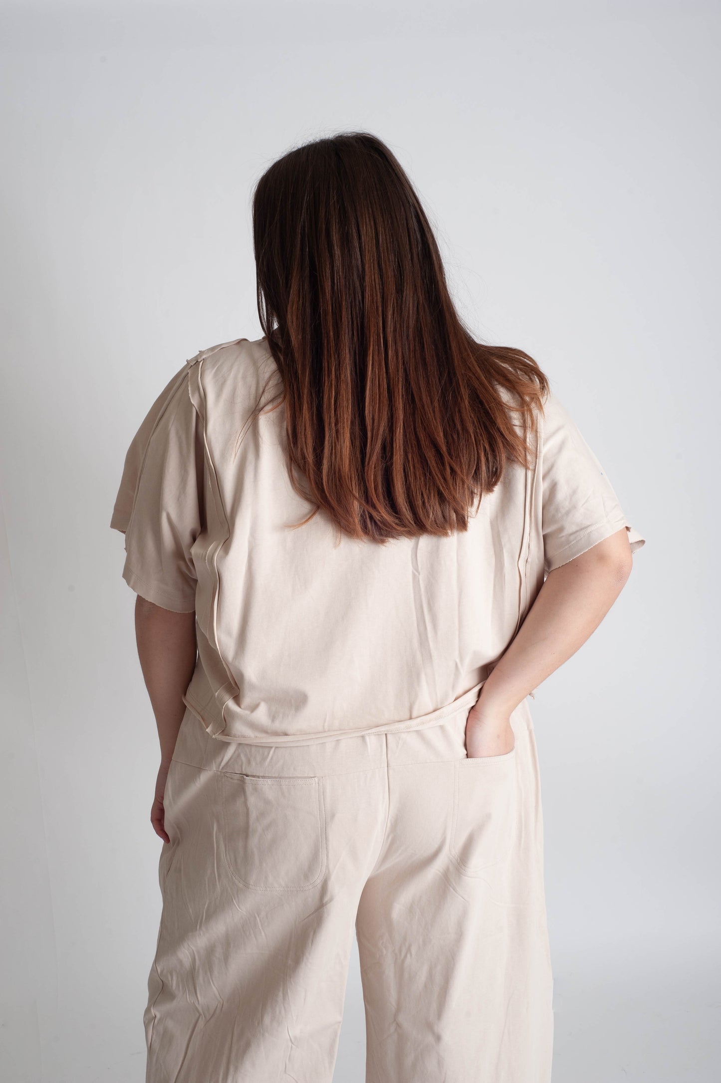 Person wearing a beige outfit against a plain background