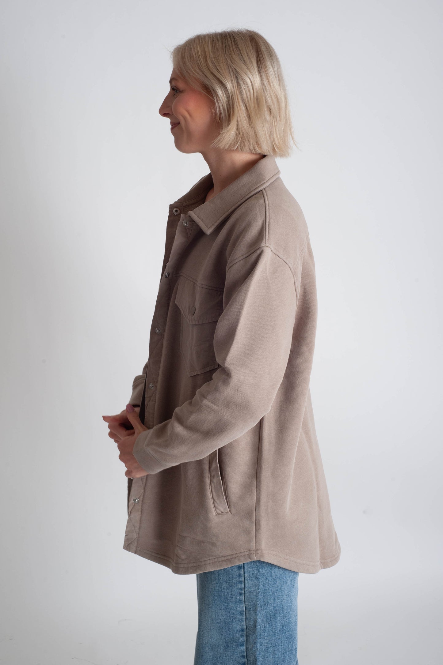 Woman wearing a beige jacket and blue jeans on a white background