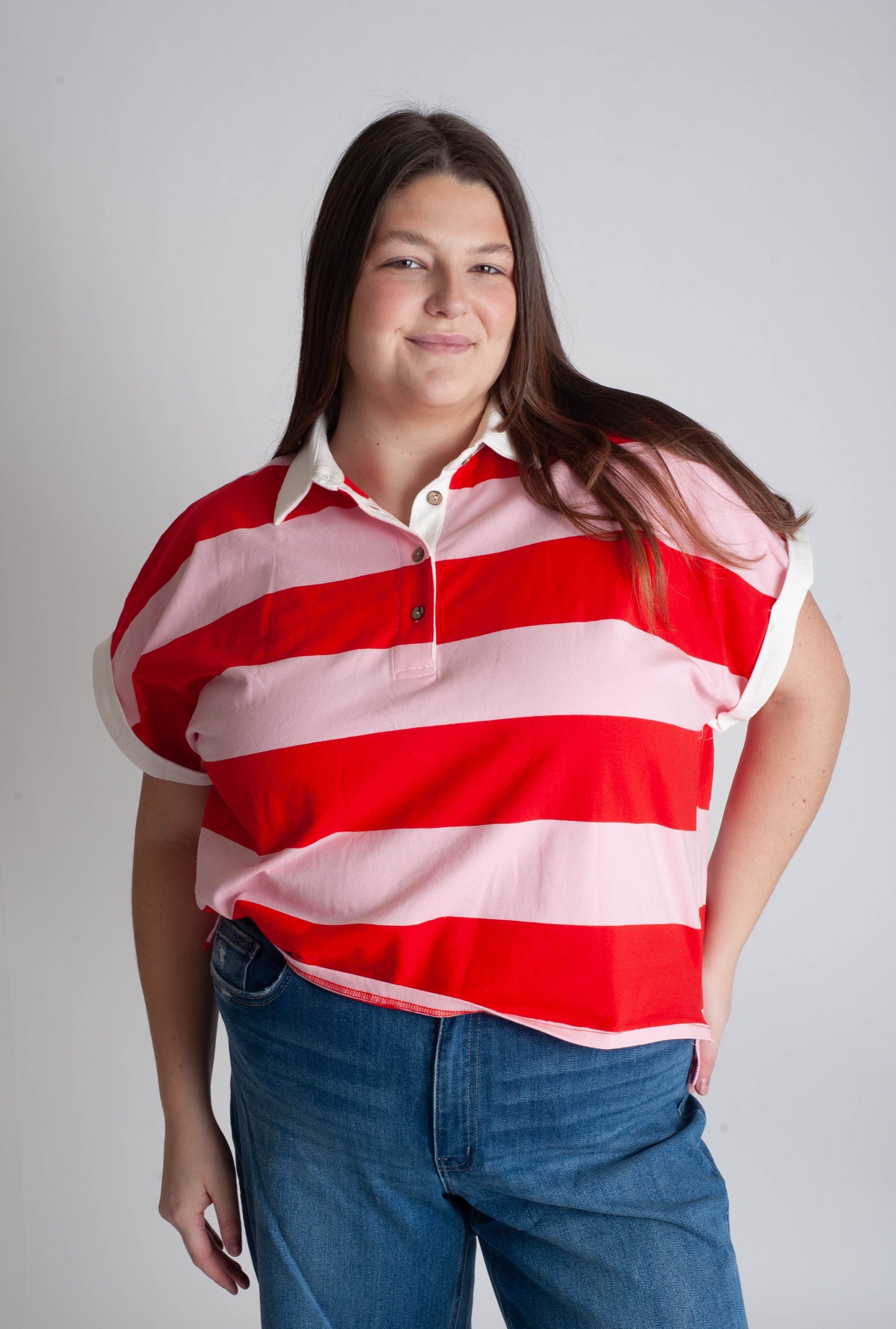 Person wearing a red and white striped shirt with blue jeans on a plain background