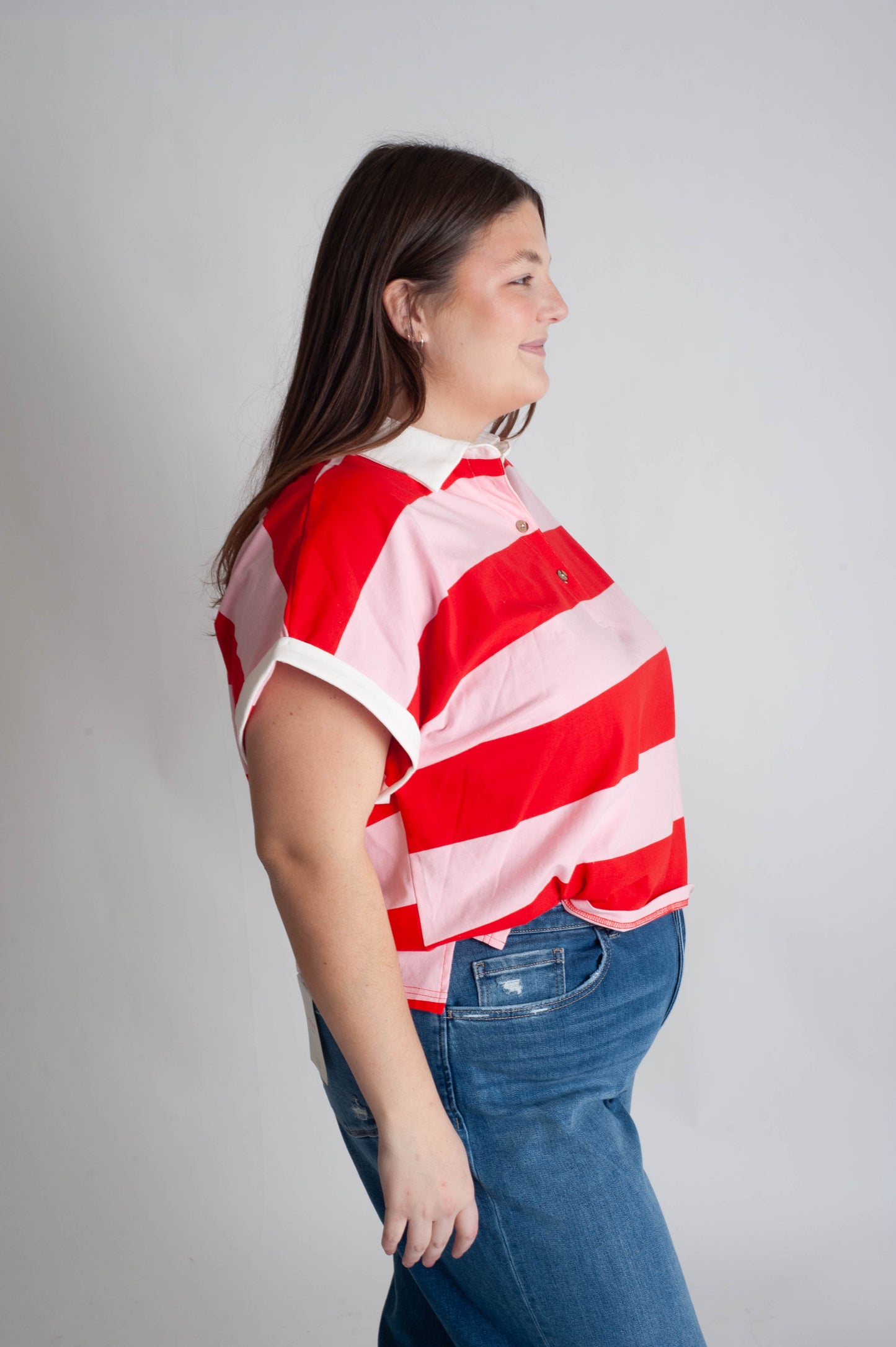 Person wearing a red and white striped shirt with blue jeans on a plain background