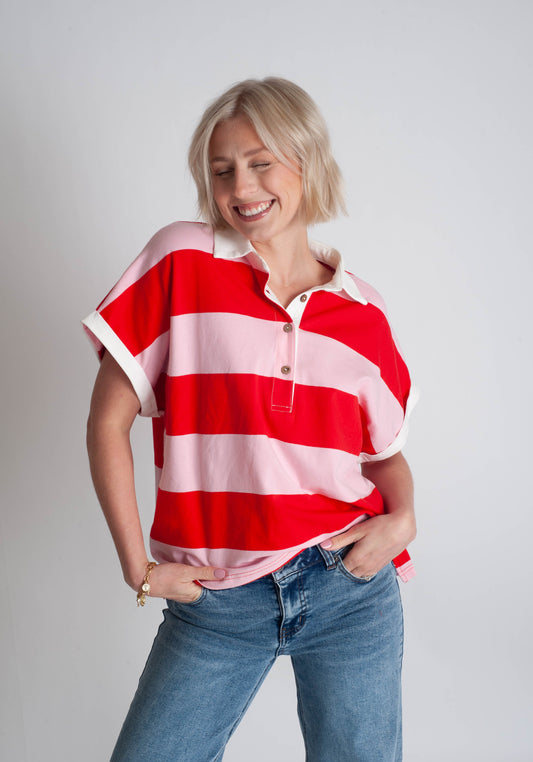 Woman wearing a red and white striped shirt with blue jeans on a plain background