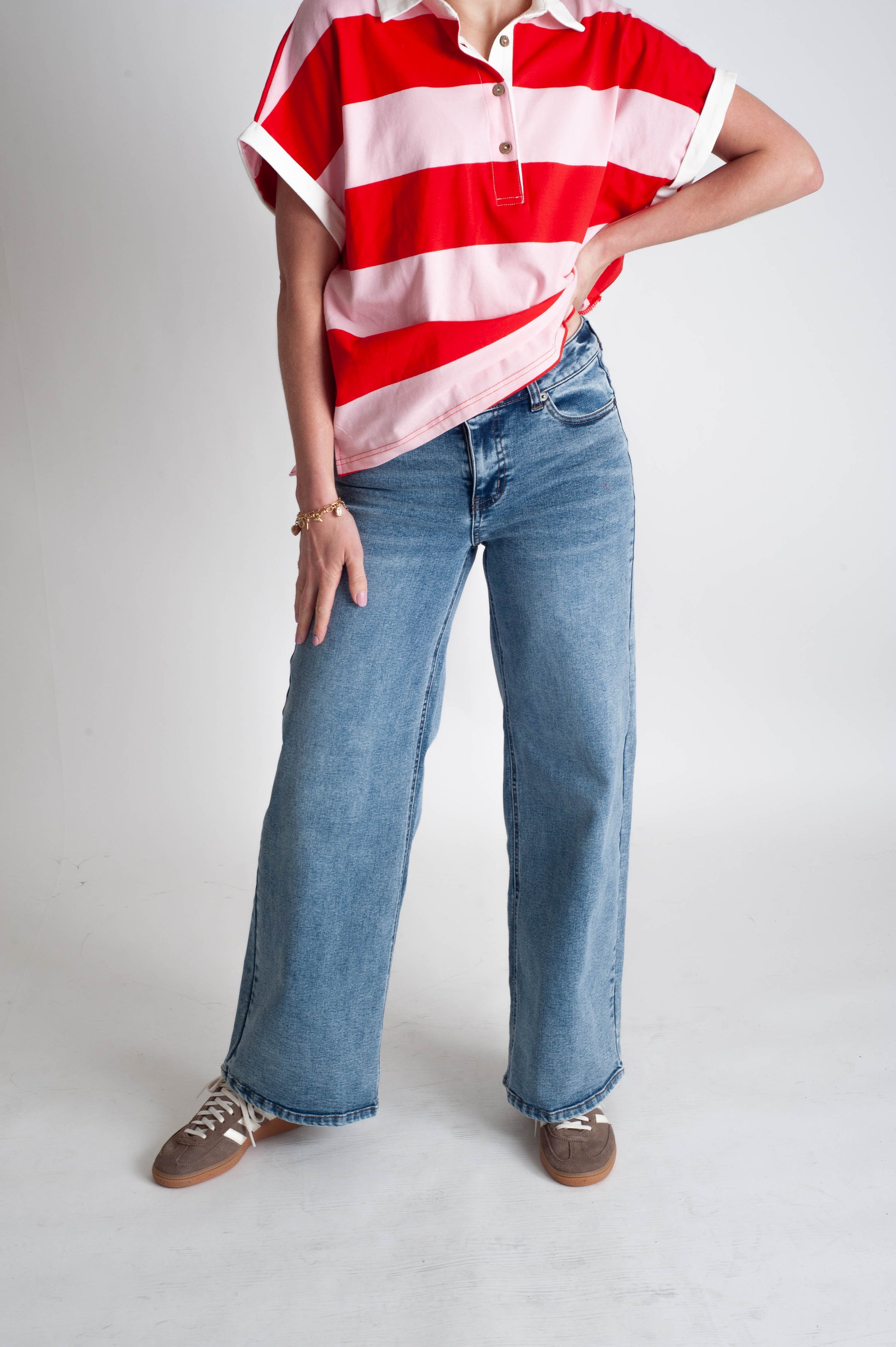 Person wearing a red and white striped shirt with blue jeans on a plain background