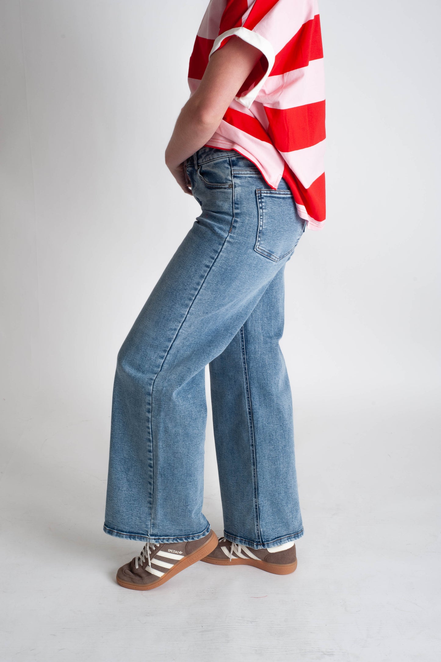 Person wearing a red and white striped shirt with blue jeans on a plain background