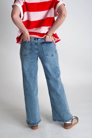 Person wearing a red and white striped shirt and blue jeans on a plain background