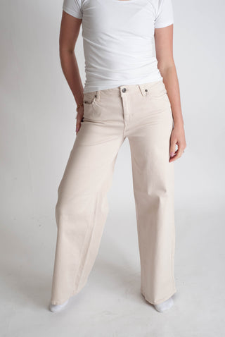 Person wearing beige pants and a white shirt on a plain background