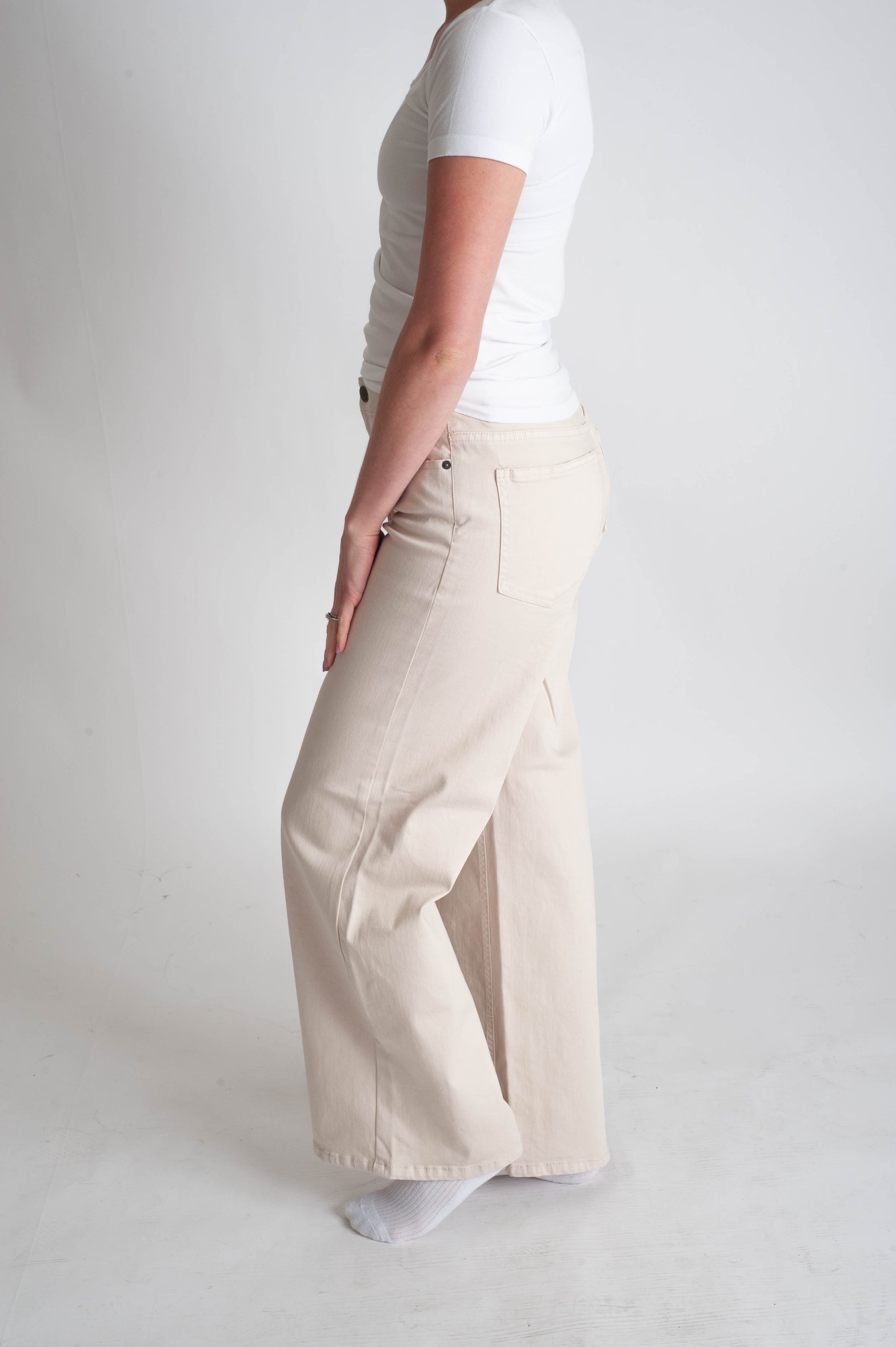 Person wearing beige wide-leg pants and a white shirt on a plain background