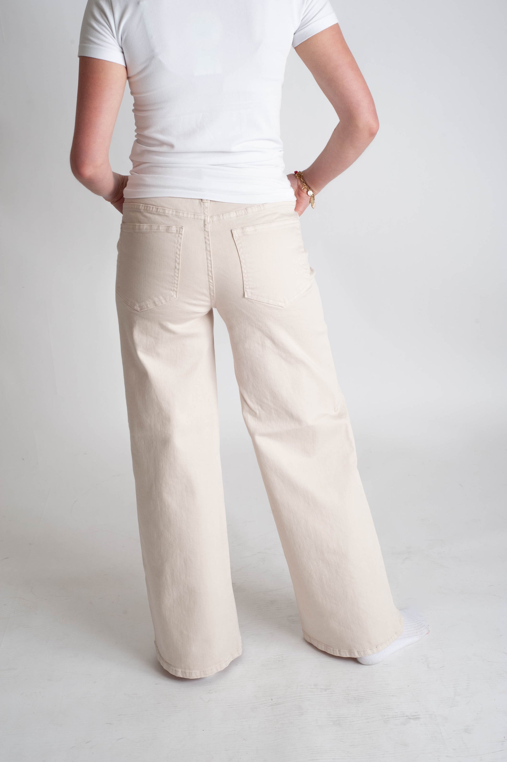 Person wearing white wide-leg pants and a white shirt on a light gray background