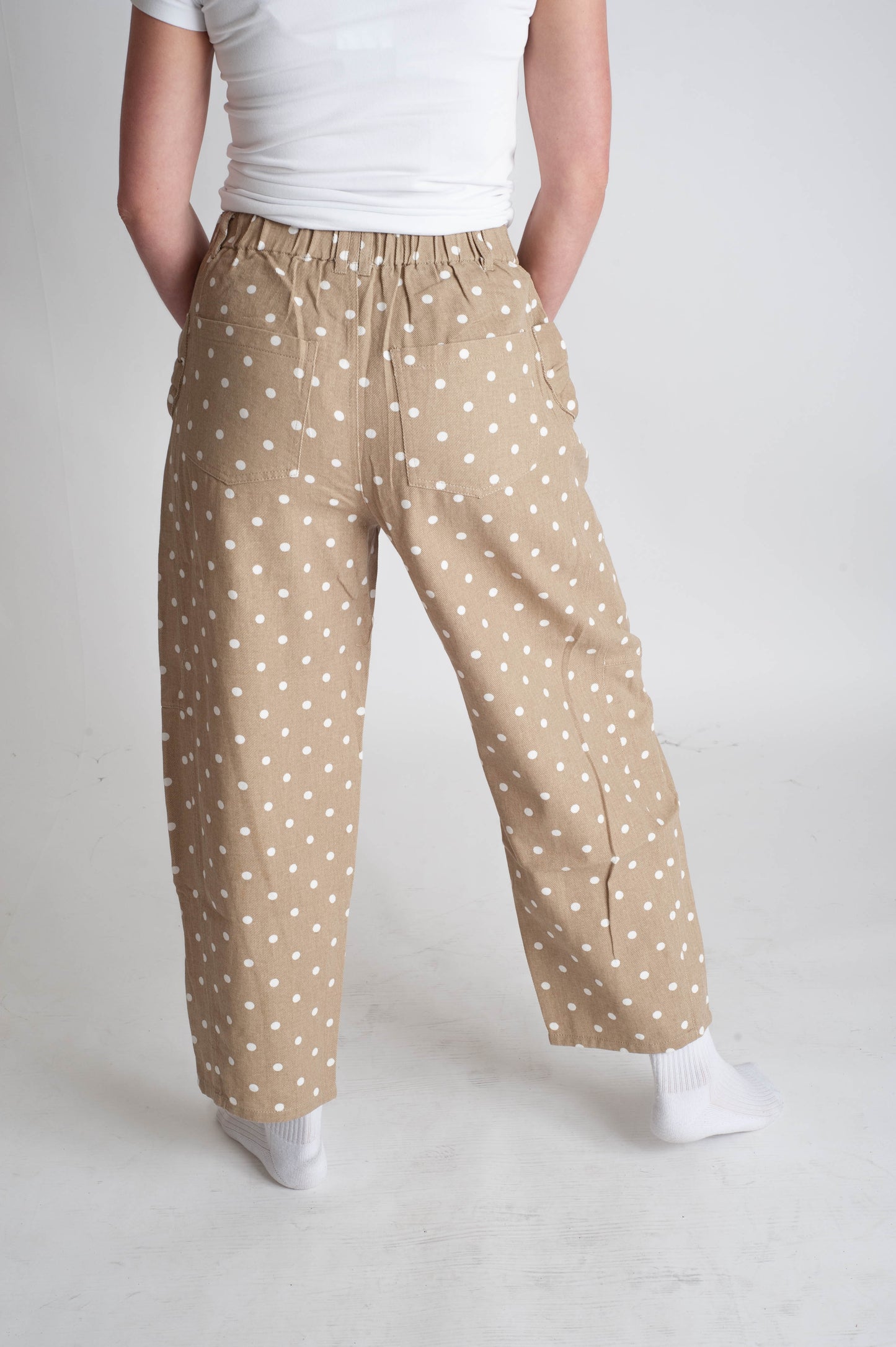 Person wearing beige polka dot pants on a plain background