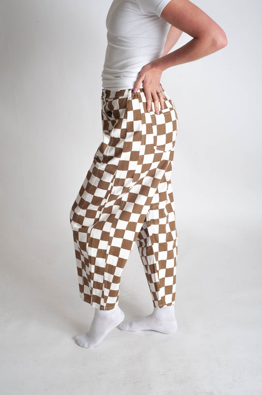 Person wearing brown and white checkered pants on a plain background