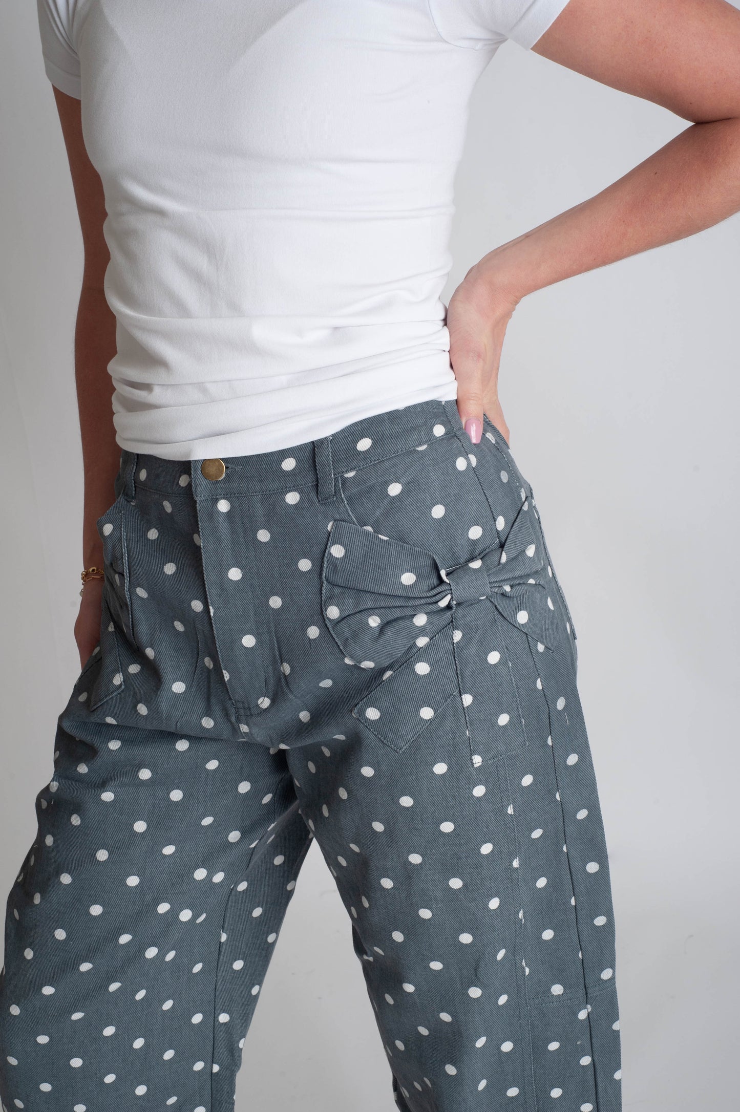 Person wearing gray pants with white polka dots on a plain background