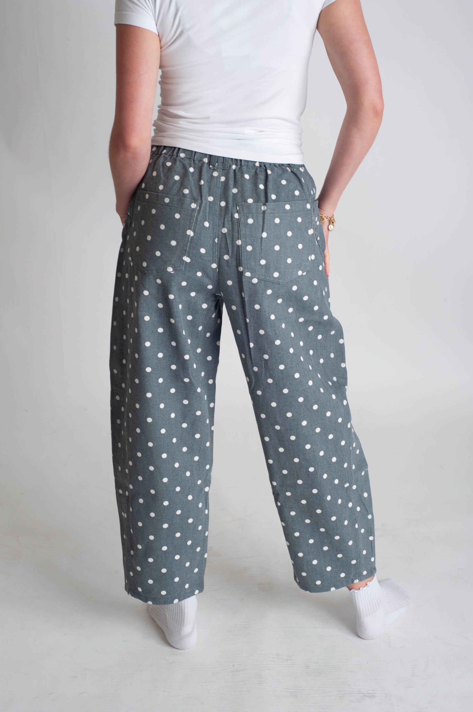 Person wearing gray pants with white polka dots on a plain background