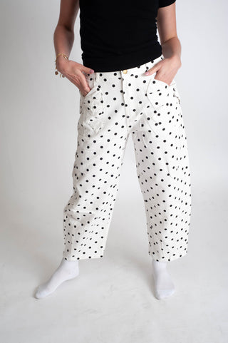Person wearing white pants with black polka dots on a plain background