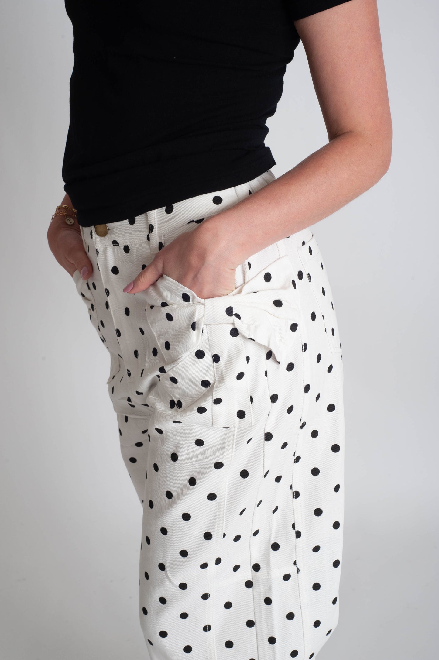 White pants with black polka dots worn by a person on a gray background