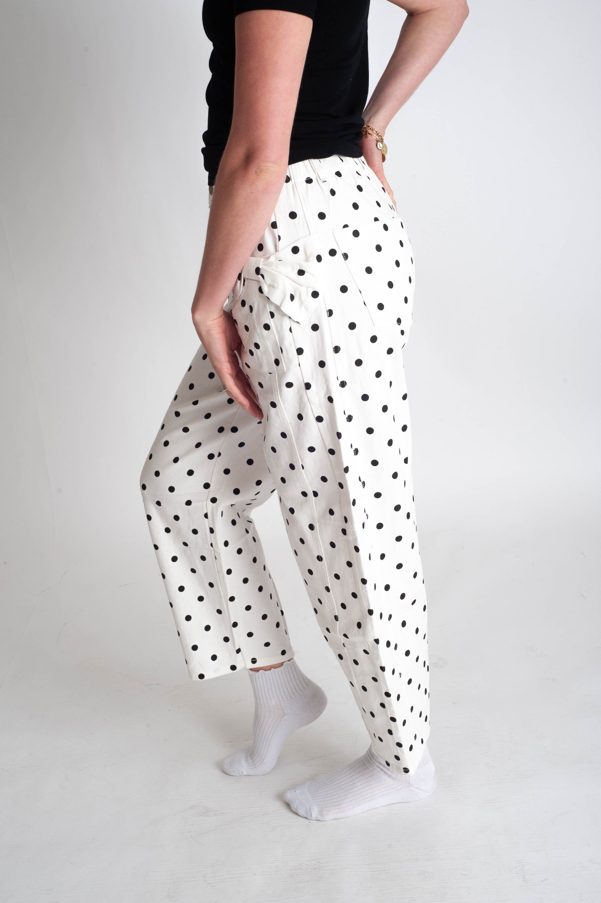 Person wearing white pants with black polka dots on a plain background