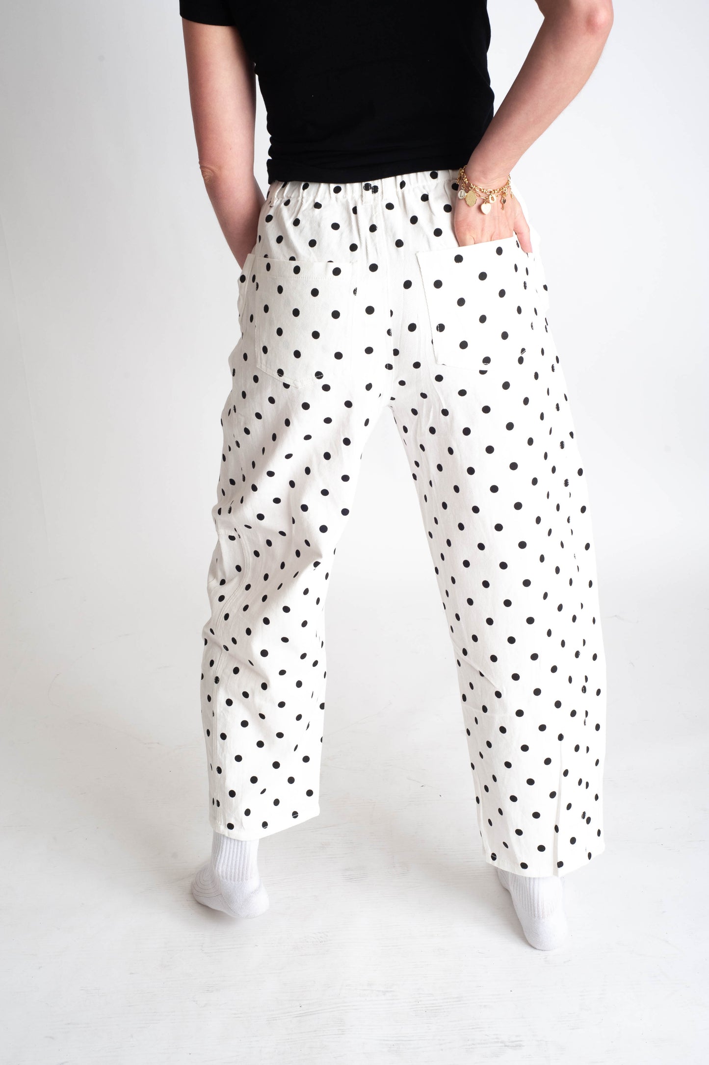 Person wearing white pants with black polka dots on a plain background