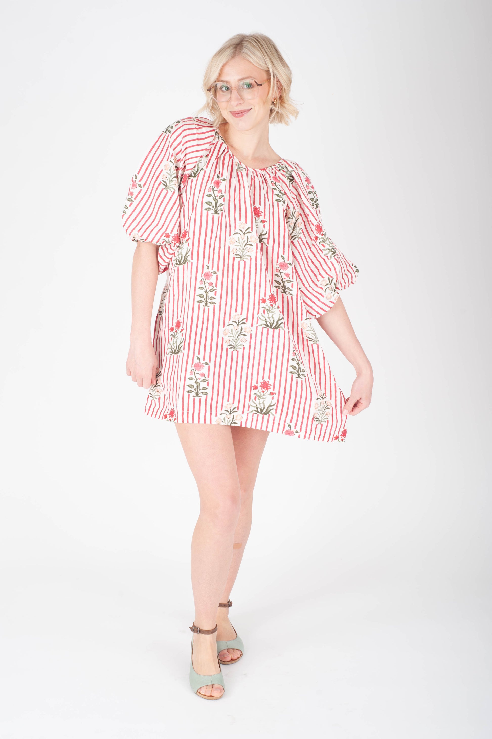 Woman wearing a red and white striped dress with floral patterns on a white background