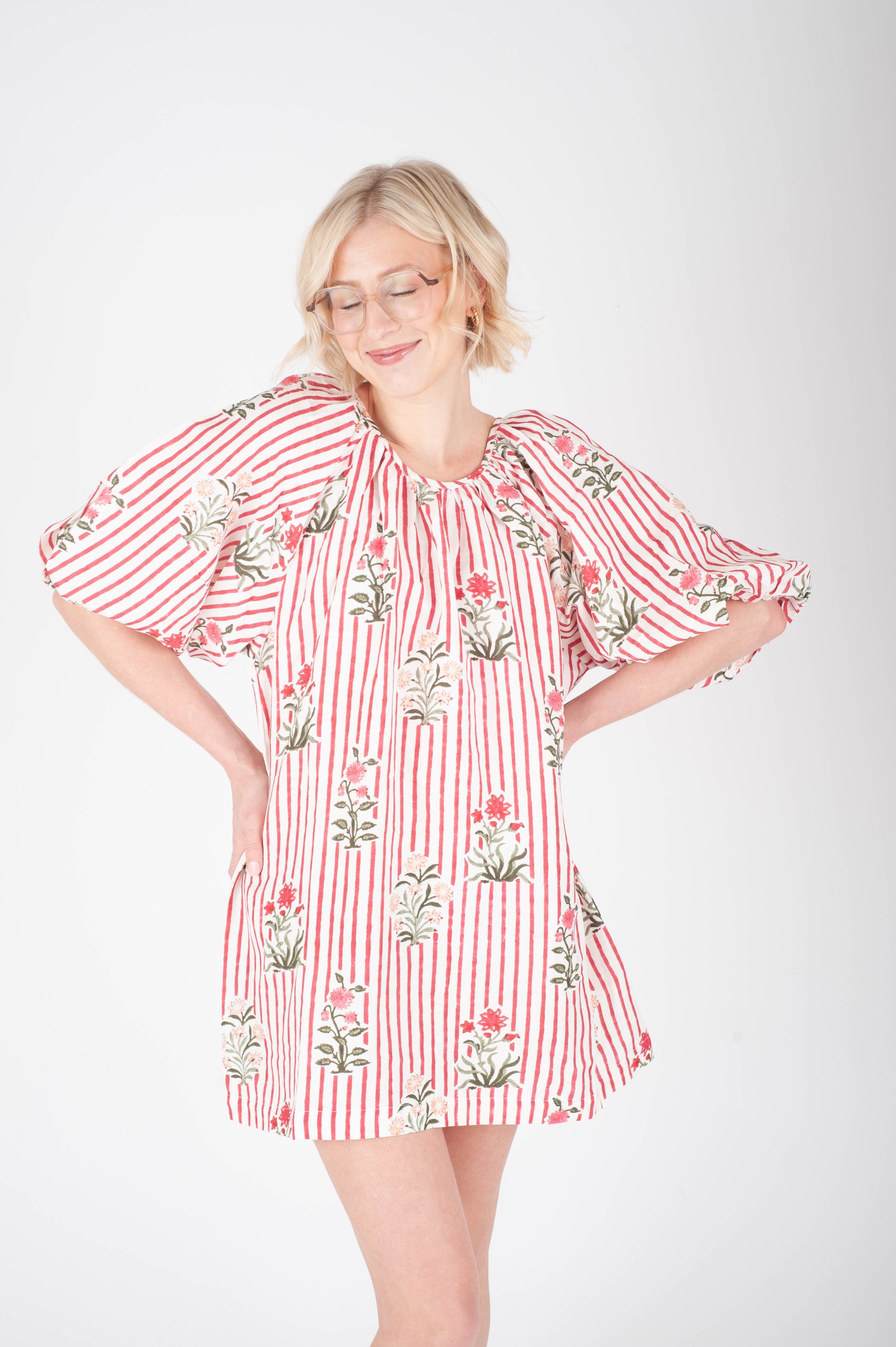 Woman wearing a red and white striped dress with floral patterns on a white background
