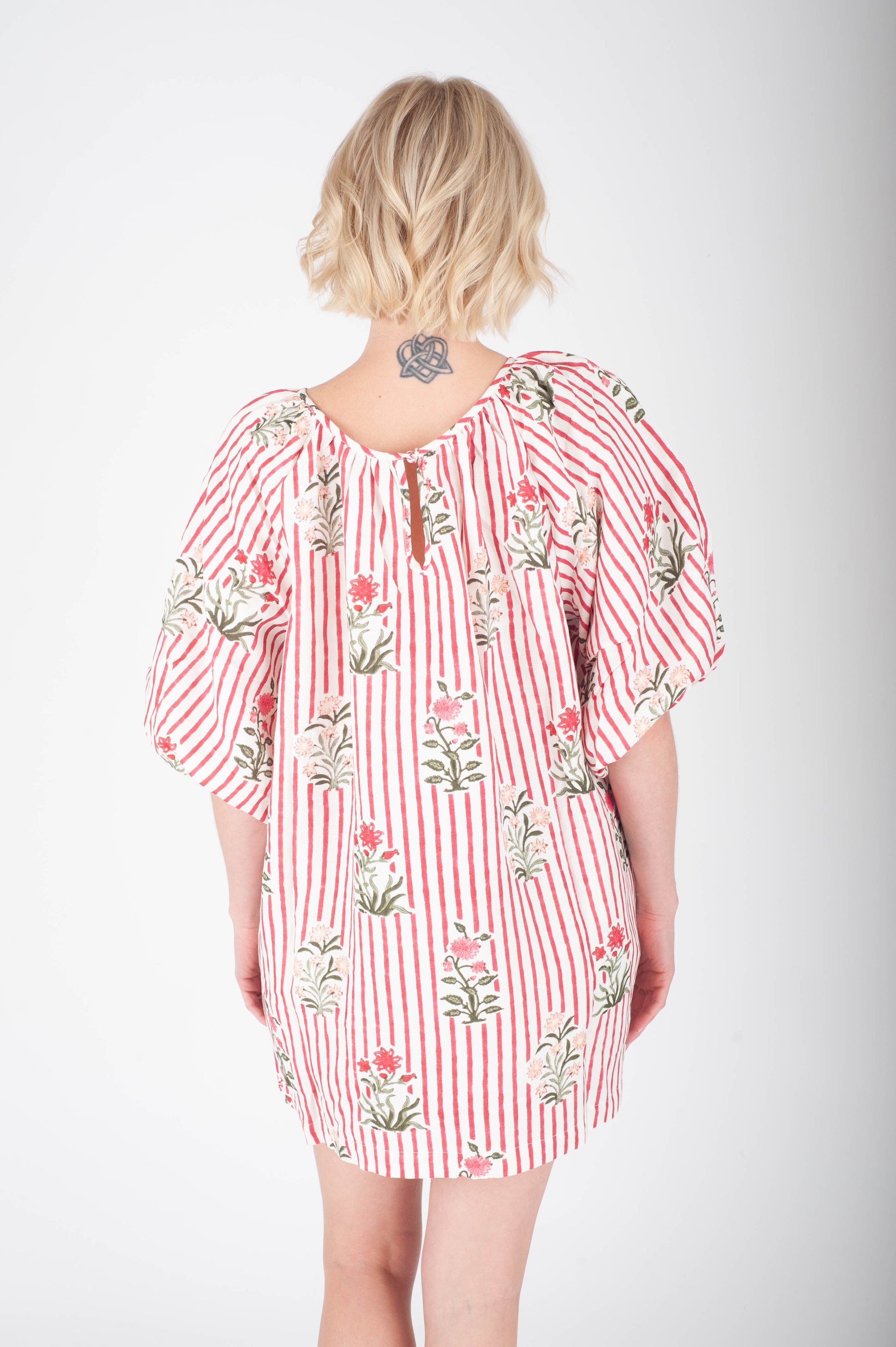 Woman wearing a red and white striped dress with floral patterns on a white background