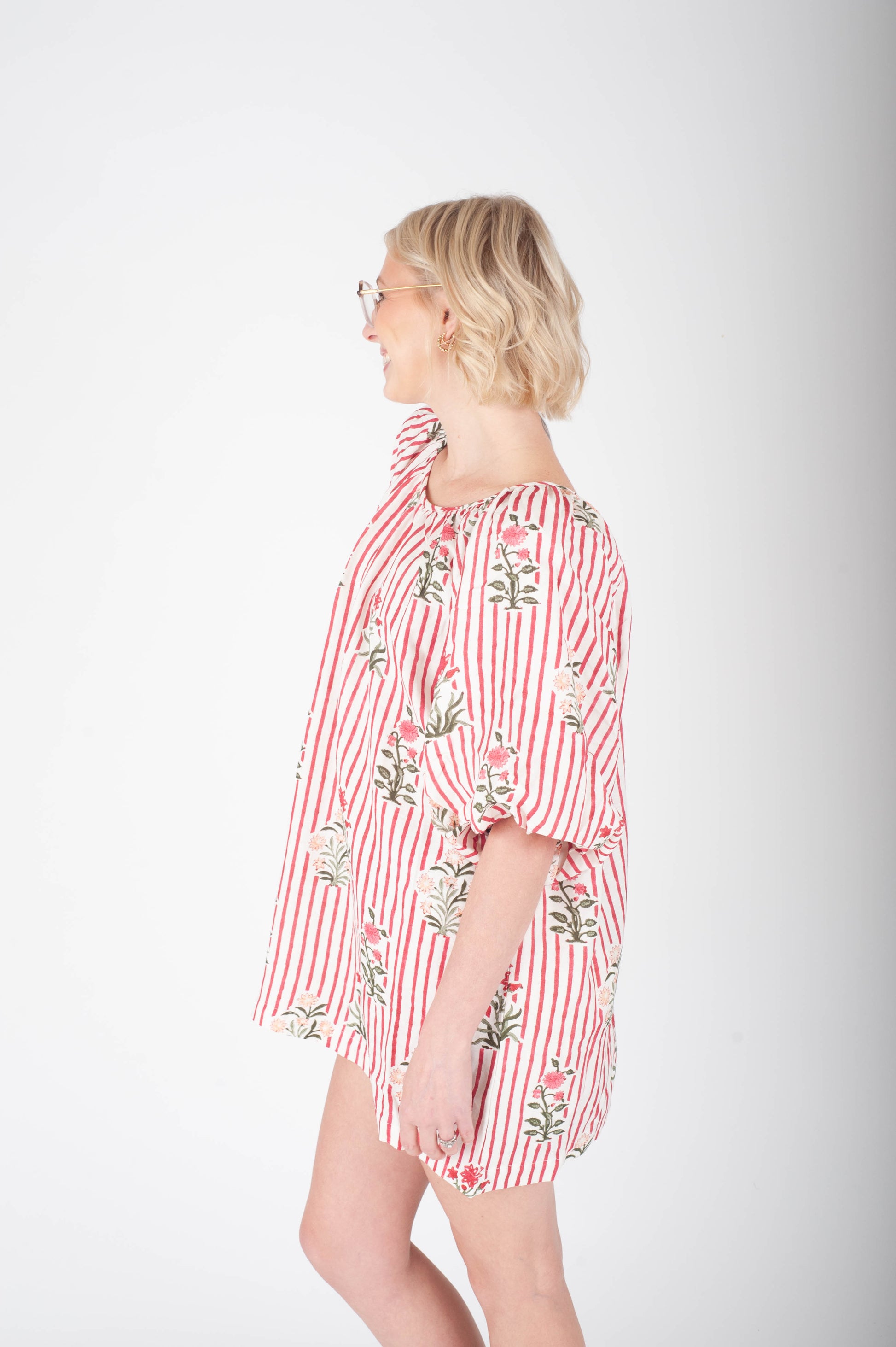 Woman wearing a red and white striped dress with floral patterns on a white background