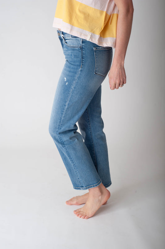 Person wearing blue jeans and a yellow and white striped shirt on a plain background