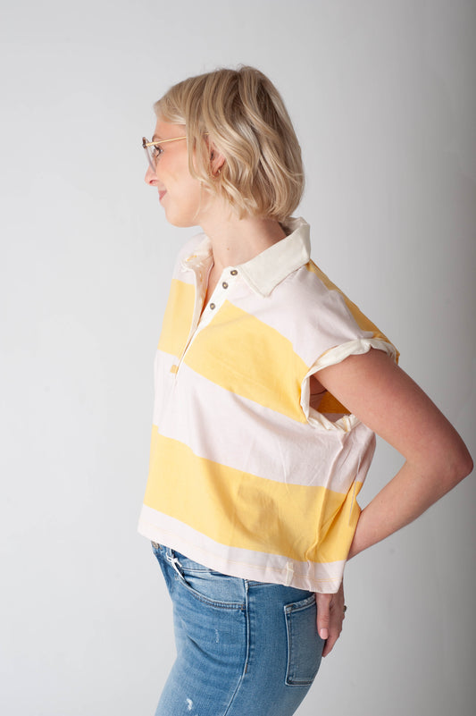 Woman wearing a yellow and white striped shirt against a plain background