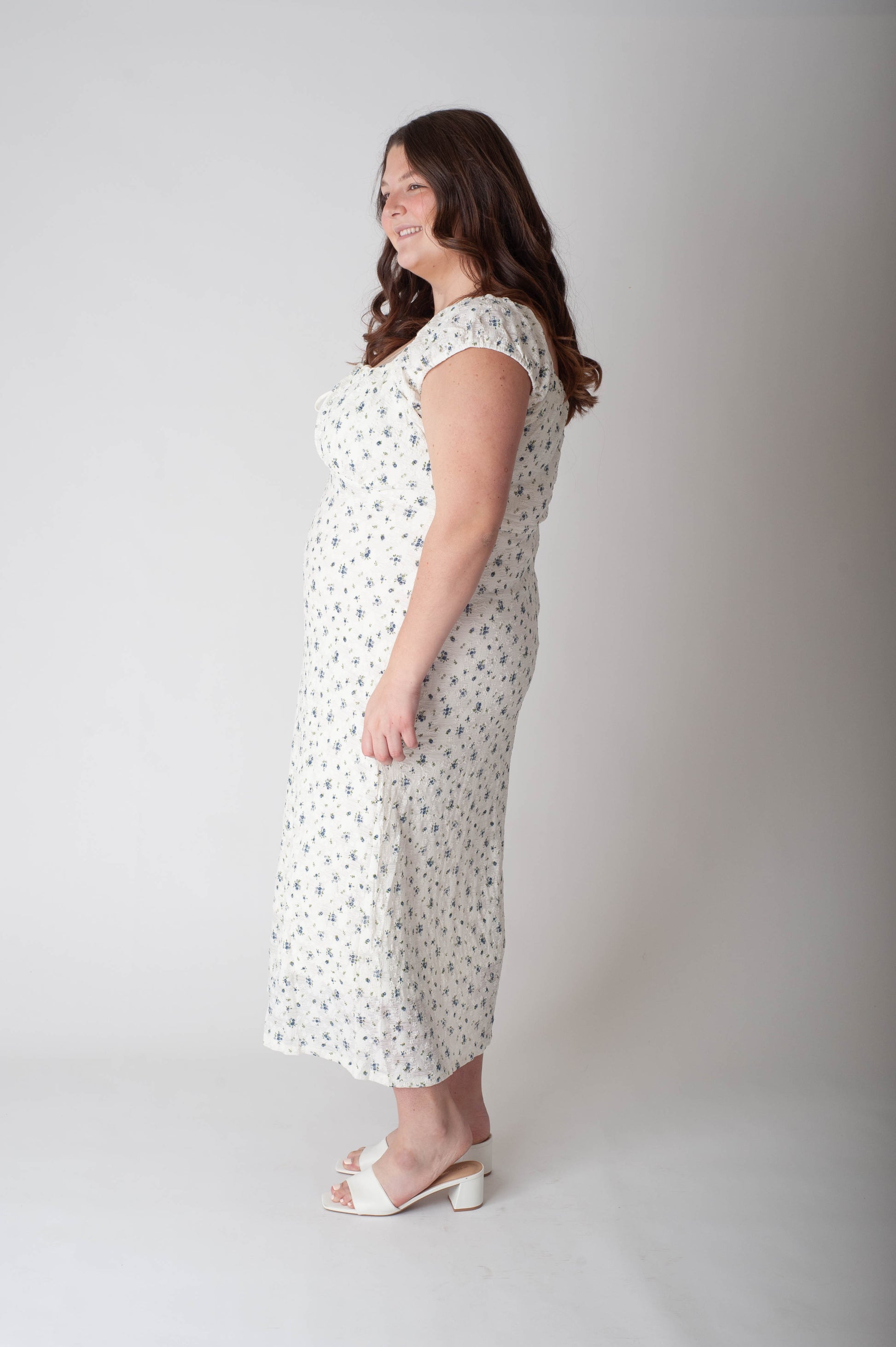Woman wearing a white dress with black patterns against a plain background