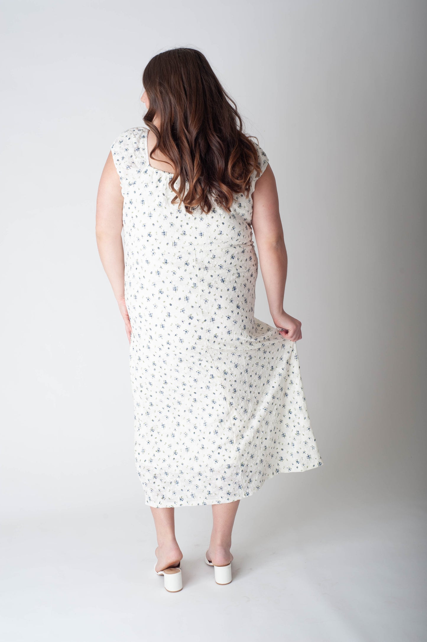 Woman wearing a white dress with black polka dots on a plain background