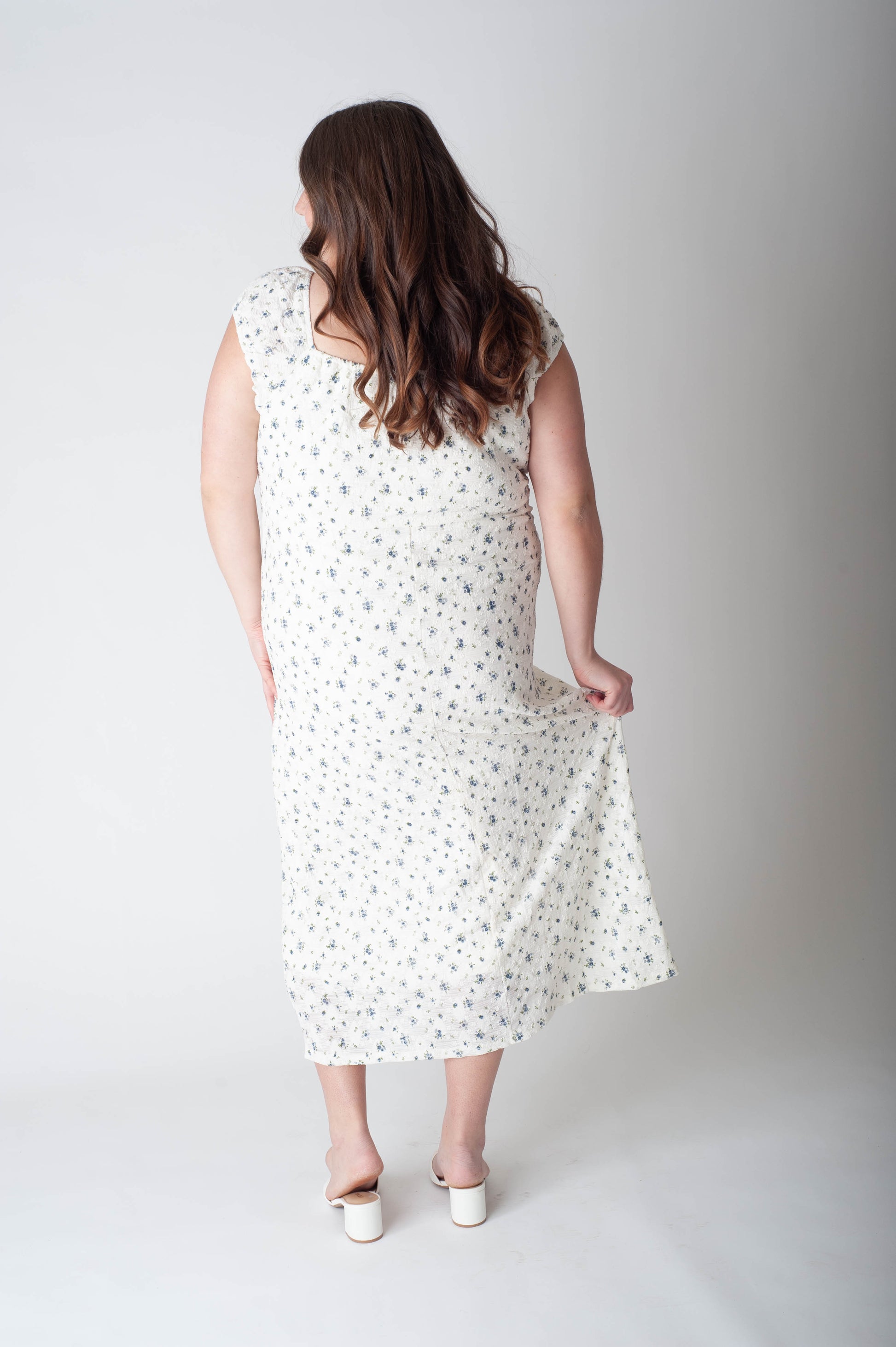 Woman wearing a white dress with black polka dots on a plain background