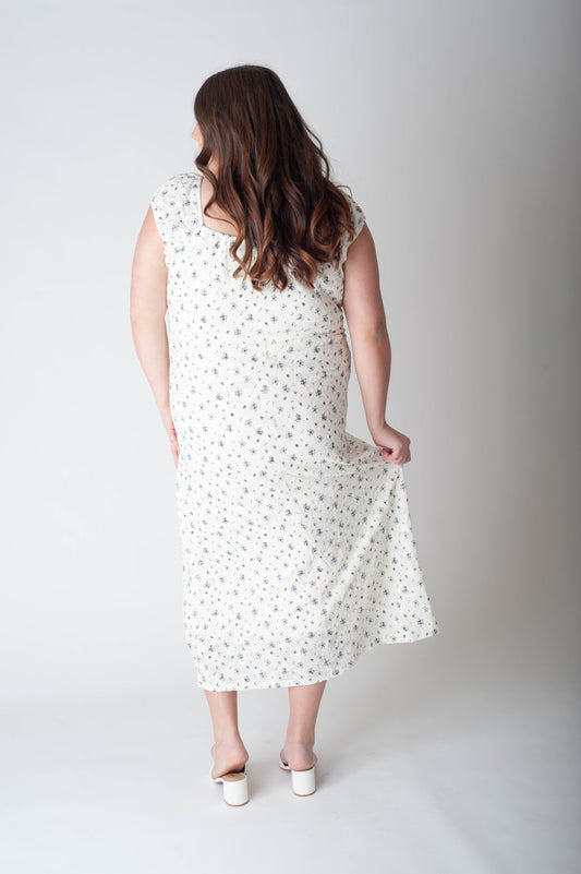 Woman wearing a white dress with black polka dots on a plain background