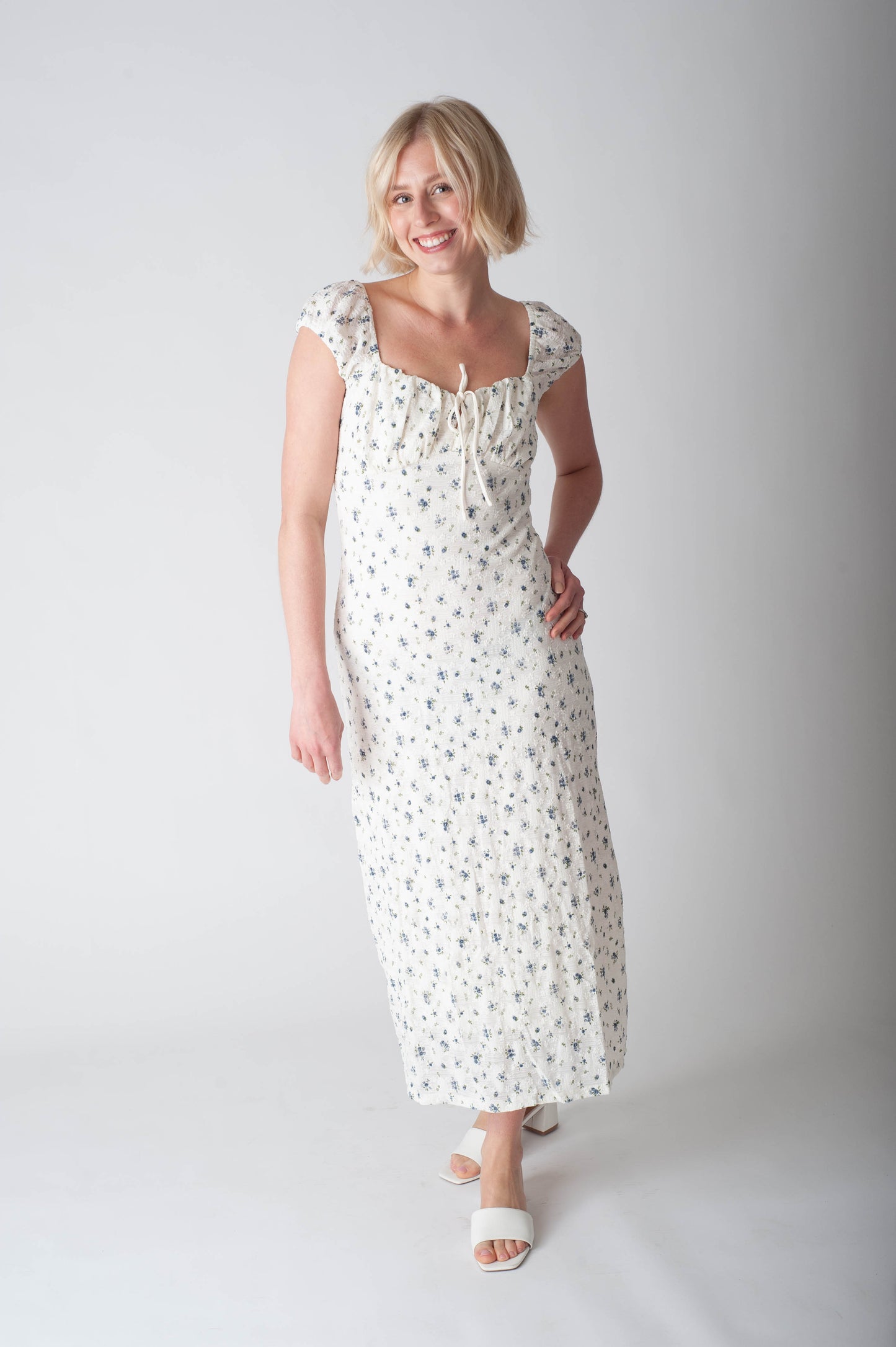 Woman wearing a white floral dress on a plain background