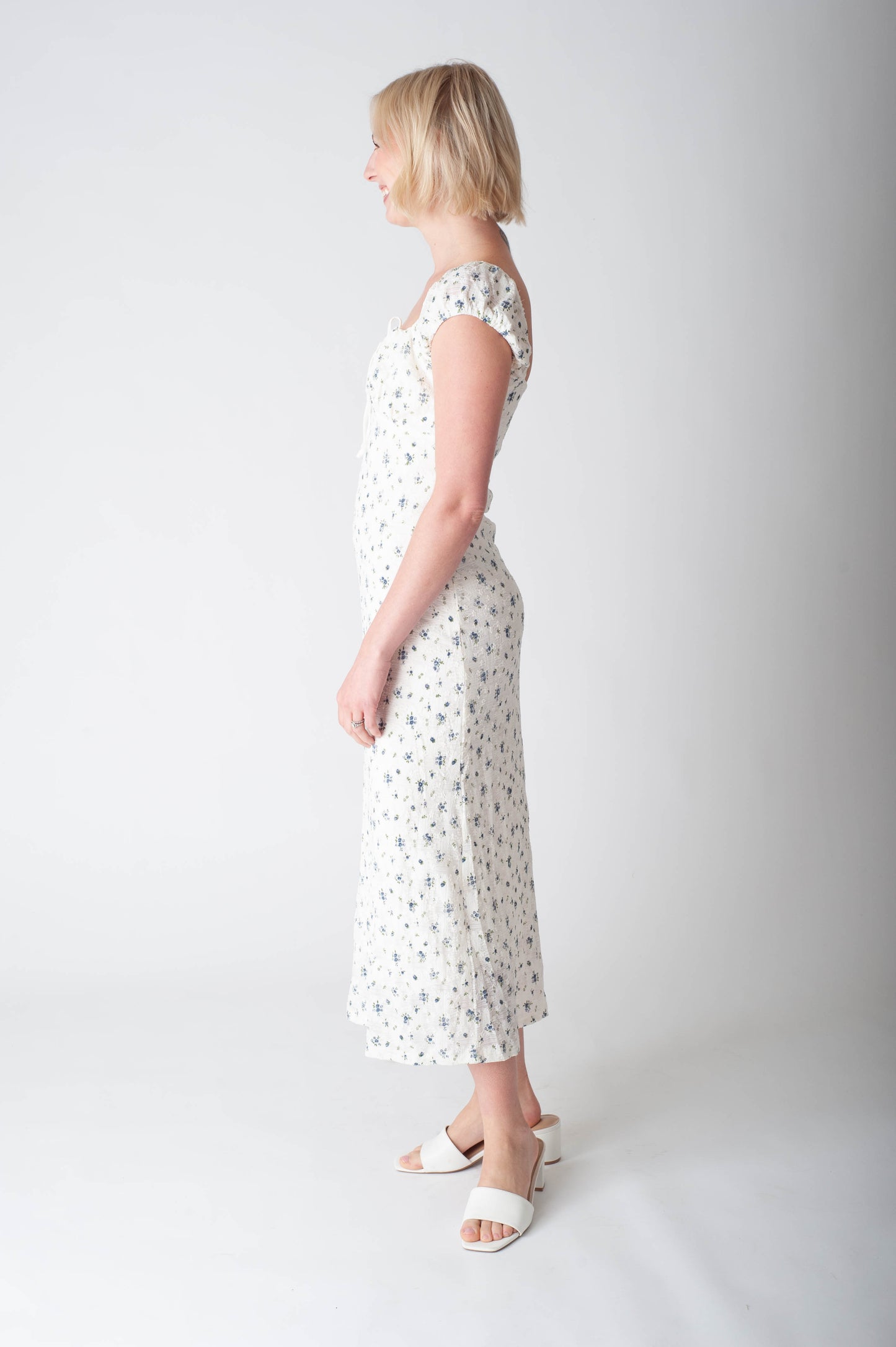 Woman wearing a white dress with black patterns on a plain background