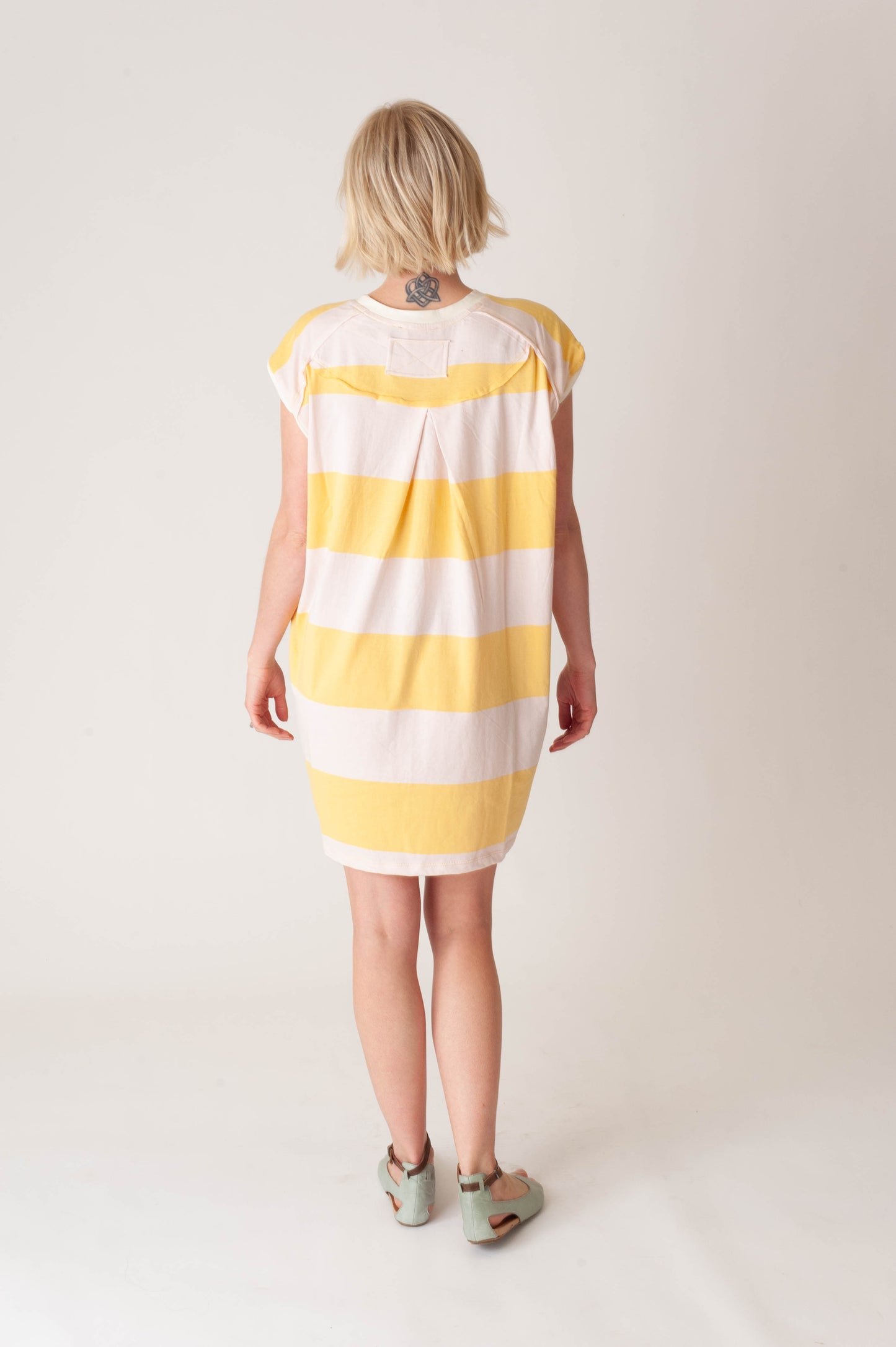 women wearing a striped yellow and pink dress on a white background