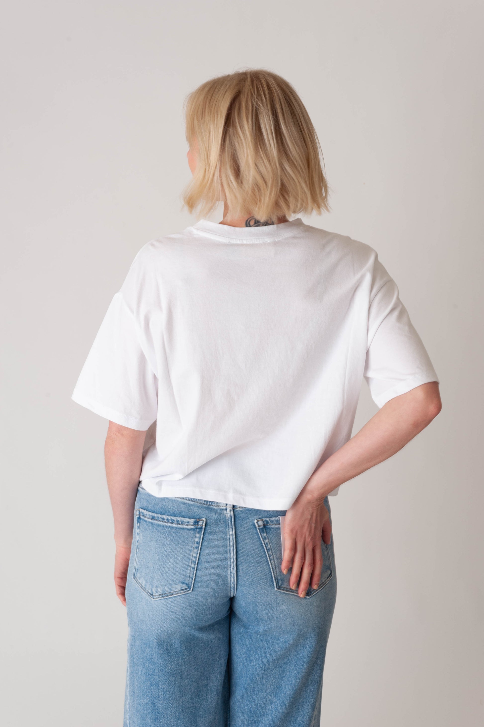 Person wearing a white t-shirt and blue jeans against a plain background