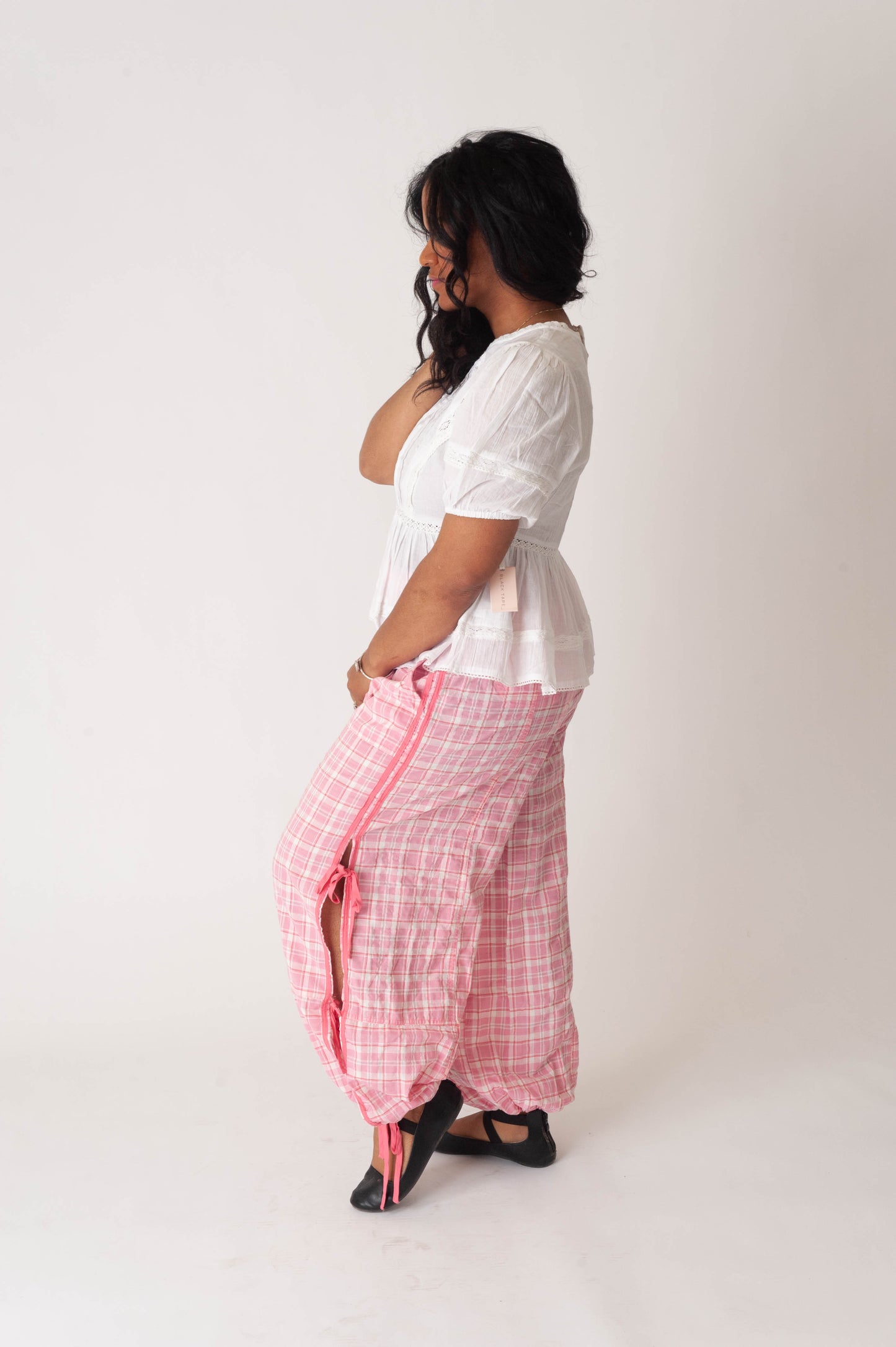 Woman wearing a white top and pink checkered dhoti on a white background